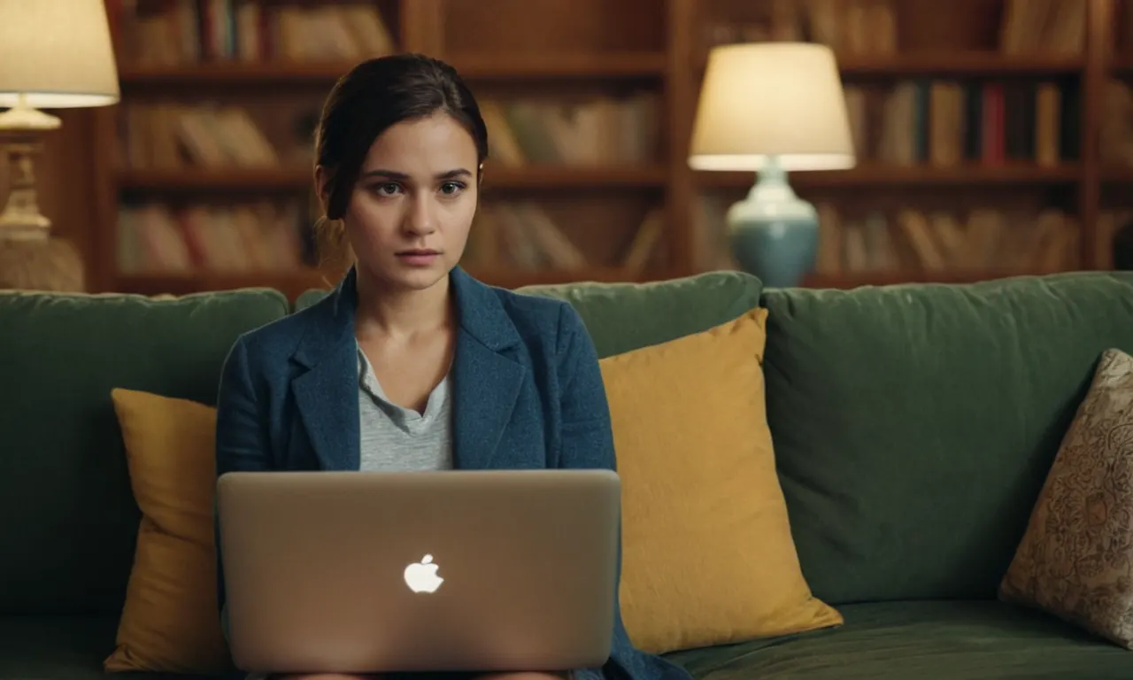 Una joven sentada en un sofá, rodeada de libros y laptop, con una expresión reflexiva.